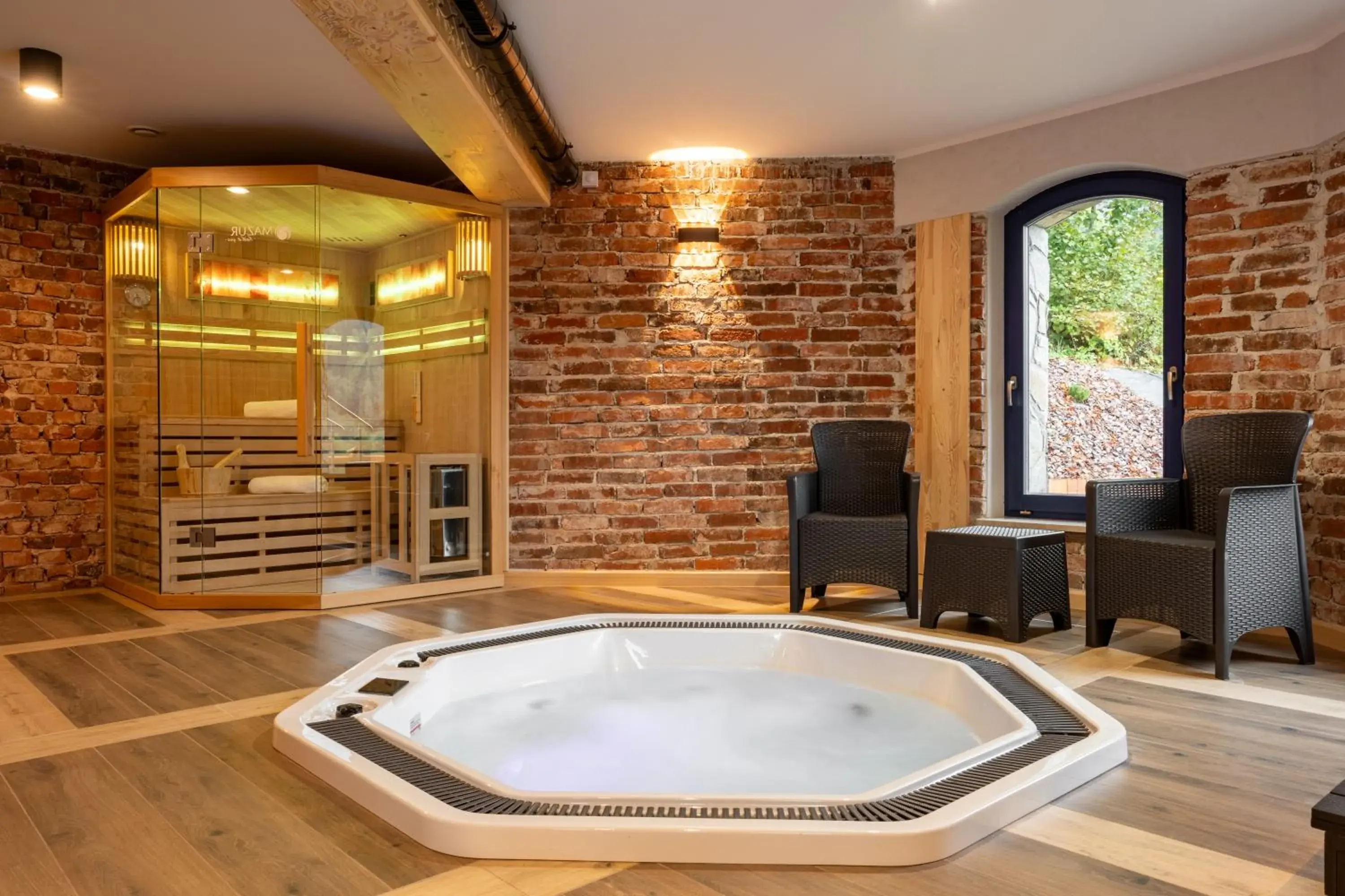Wanna z hydromasażem i sauna w sali z ceglanymi ścianami